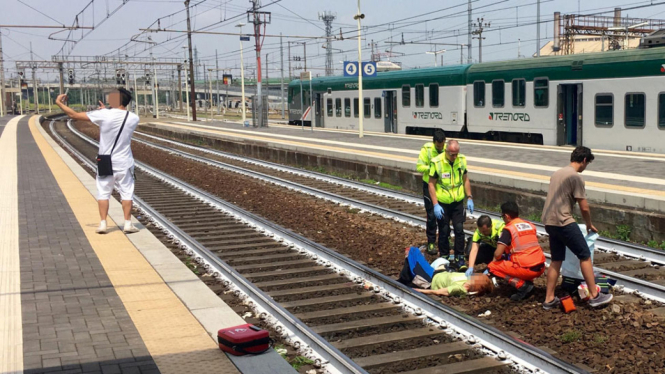 Pria berswafoto dengan latar belakang petugas yang sedang membantu korban yang ditrabrak kereta api di Piacenza, Italia utara. - ANSA/GIORGIO LAMBRI/QUOTIDIANO LIBERTA