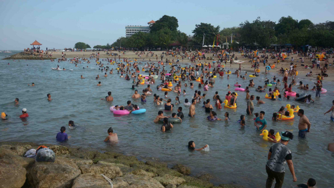 Wisatawan berenang di kawasan Pantai Sanur, Bali