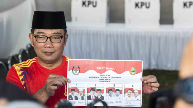 Calon Gubernur Jawa Barat nomor urut satu Ridwan Kamil menunjukkan surat suara sebelum menggunakan hak pilih di Pilgub Jabar