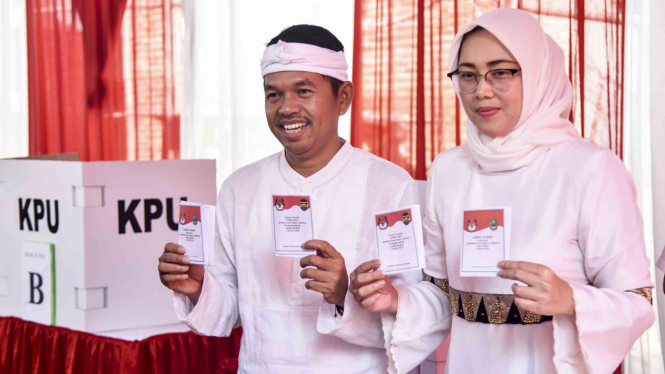 Calon Wakil Gubernur Jabar nomor urut empat Dedi Mulyadi (kiri) didampingi istri Anne Ratna Mustika, menunjukkan surat suara saat menggunakan hak pilih