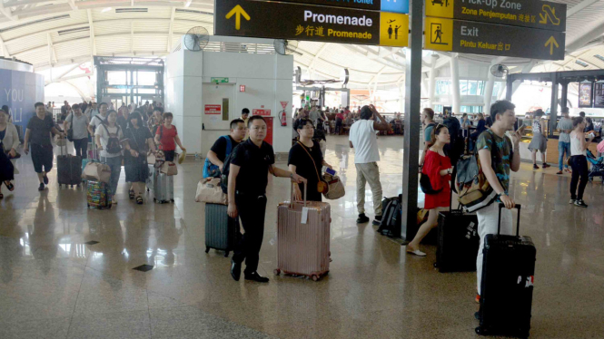 Sejumlah penumpang beristirahat menunggu jadwal penerbangan di Bandara Ngurah Rai, Bali.