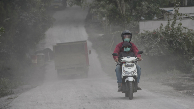 Pengendara melintasi kawasan yang terpapar abu vulkanis Gunung Agung di Desa Pemuteran, Karangasem, Bali, Jumat (29/6/2018).