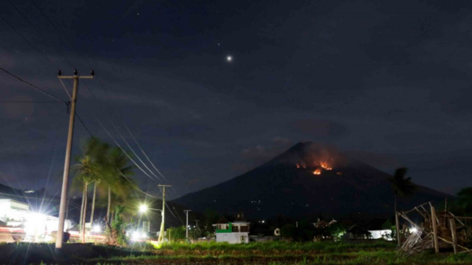Api membakar hutan lereng Gunung Agung setelah terjadinya lontaran batu pijar dari kawah terlihat dari Amed, Karangasem, Bali, Selasa, 3 Junli 2018.