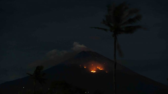 Api membakar hutan lereng Gunung Agung setelah terjadinya lontaran batu pijar dari kawah terlihat dari Desa Culik, Karangasem, Bali