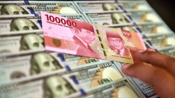 Petugas jasa penukaran valuta asing memeriksa lembaran mata uang rupiah dan dolar AS di Jakarta.