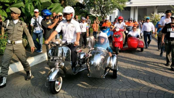 Anies Baswedan dan Sandiaga Uno mengendarai Vespa.