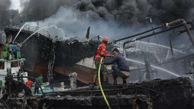 Petugas pemadam kebakaran memadamkan api yang membakar kapal di Pelabuhan Benoa