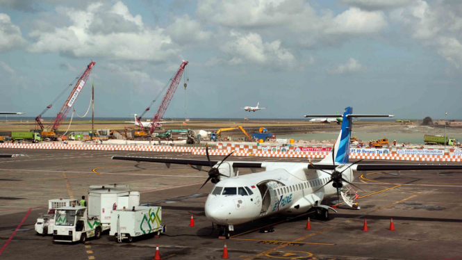 Sebuah pesawat komersial parkir di dekat kawasan proyek perluasan apron di Bandara Ngurah Rai, Denpasar