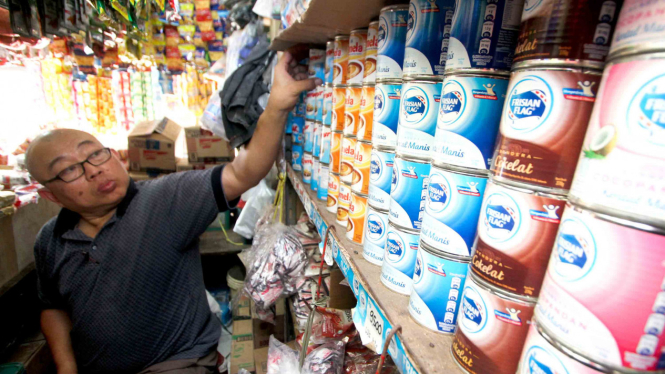 Pedagang menunjukkan produk susu kental manis kemasan yang dijual