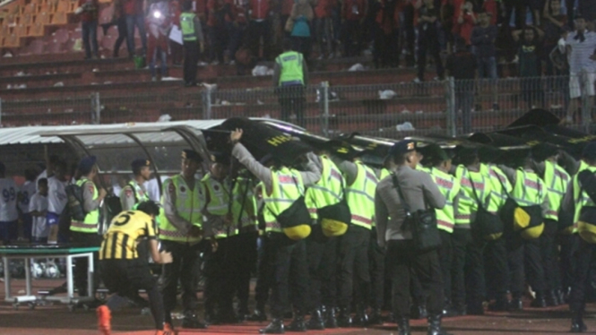 Pemain TImnas Malaysia U-19 menghindari timpukan penonton
