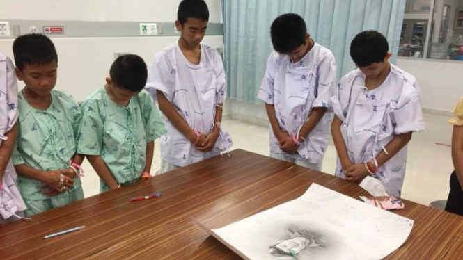 Para remaja Thailand memberikan penghormatan di depan dengan gambar Saman Gunan.