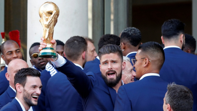 Striker tim nasional Prancis, Olivier Giroud memamerkan trofi Piala Dunia 2018