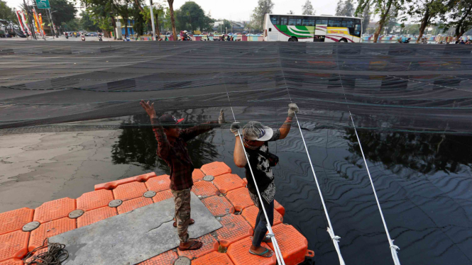 Penutupan jaring untuk mengurangi bau di Kali Item, dekat Wisma Atlet Kemayoran