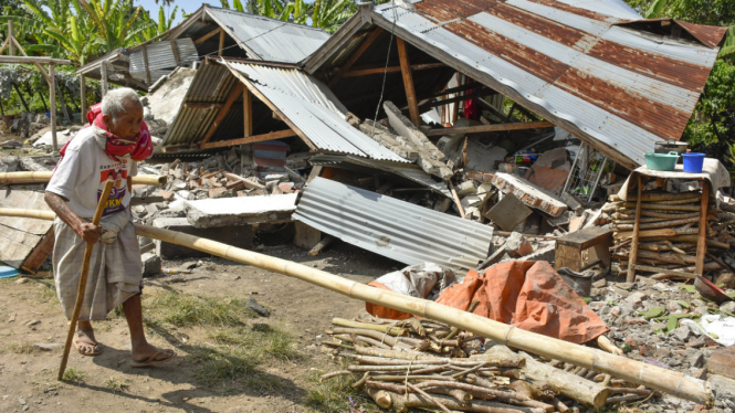 Warga berjalan di depan rumah yang roboh akibat gempa di Desa Sajang, Kecamatan Sembalun, Selong, Lombok Timur, NTB, Minggu (29/7/2018). 