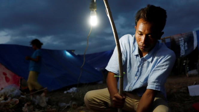 Seorang warga di Senggigi, Lombok, yang khawatir akan gempa susulan memasang lampu di depan tenda tempat mereka berlindung. - Reuters