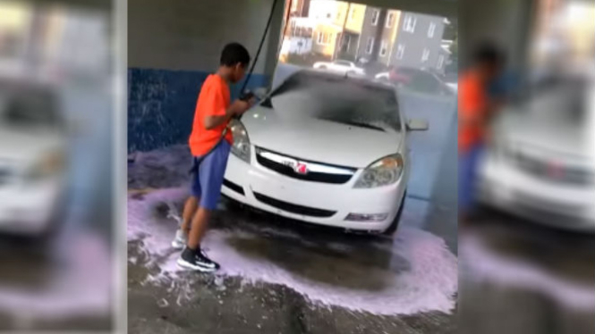 Seorang bocah mencuci mobil.
