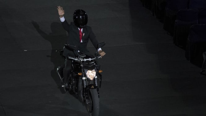 Presiden Joko Widodo mengendarai motor sambil melambaikan tangan saat pembukaan Asian Games ke-18 tahun 2018 di Stadion Utama Gelora Bung Karno, Jakarta, Sabtu (18/8/2018).