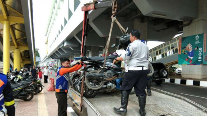 Petugas Dinas Perhubungan mengangkuti sepeda motor yang parkir liar di sepanjang jalan protokol kawasan Jakabaring Sport City, Palembang, pada Kamis, 23 Agustus 2018.