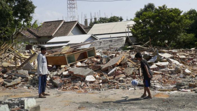 Anak-anak bermain bola di antara reruntuhan bangunan setelah serangkaian gempa besar mengguncang kota Lombok.