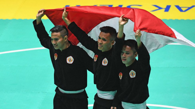Tim silat Indonesia peraih medali emas Nunu Nugraha (tengah), Asep Yuldan Sani (kiri) dan Anggi Faisal Mubarok (kanan) merayakan kemenangan dengan membentangkan bendera merah putih usai meraih medali emas dalam final beregu putra pencak silat seni Asian G