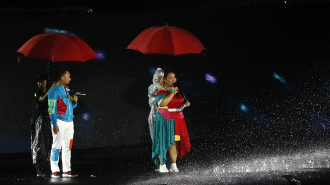 Host acara Penutupan Asian Games 2018 Ronal Surapraja dan Tike Priatnakusumah di bawah guyuran hujan.