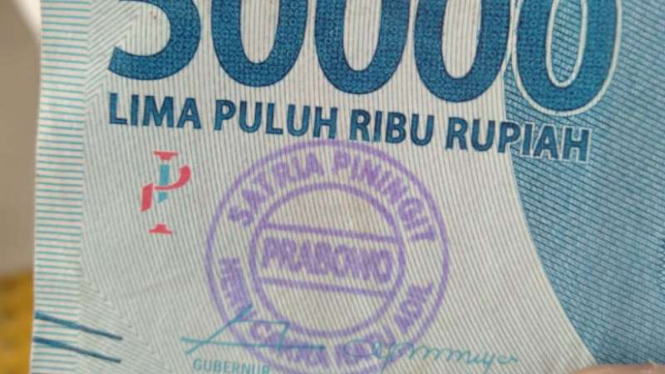 Seorang warga Tangerang, Banten, menerima uang pecahan Rp50.000 yang pada lembarannya terdapat stempel bertulis "Prabowo-Satria Pinigit; Heru Cakra Ratu Adil".