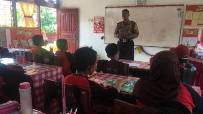 Albert Amarta, personel Kepolisian Resor Kota Padang, saat bertugas rutin mengajar bahasa Inggris untuk murid-murid sekolah dasar di Kecamatan Pauh pada Senin, 17 September 2018.