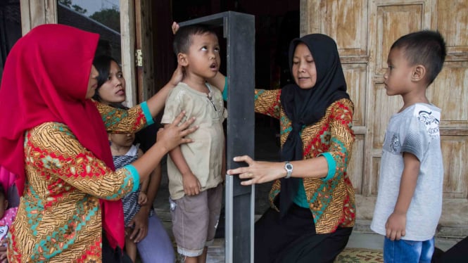 Petugas Puskesmas mengukur tinggi badan sebelum memberikan pelayanan kesehatan imunisasi kepada balita di rumah salah satu warga Desa Srawung, Gesi, Sragen, Jawa Tengah