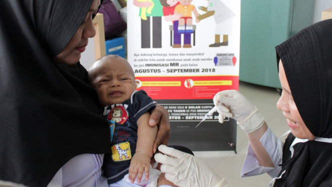 Petugas menyuntikan Vaksin Campak dan Rubella (MR) kepada bayi saat dilakukan imunisasi di Puskesmas Darussalam, Banda Aceh, Rabu (19/09). - ANTARA FOTO/AMPELSA