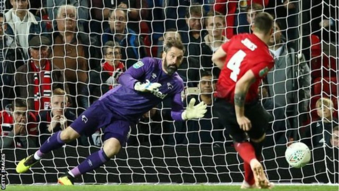 Kiper Scott Carson menahan tendangan bek Manchester United, Phil Jones, dan memastikan kemenangan Derby. - Getty Images