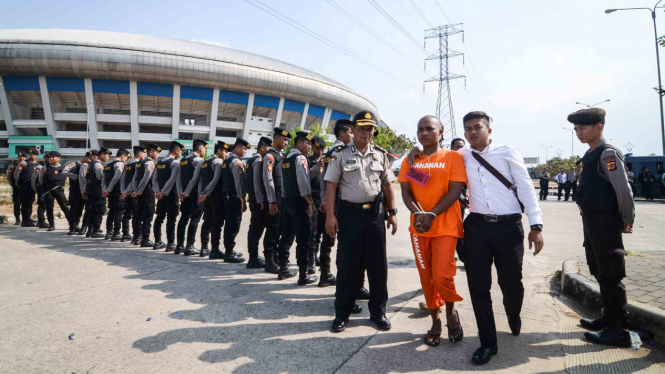 Petugas Polrestabes Bandung membawa seorang tersangka saat menggelar rekonstruksi pengeroyokan yang dilakukan oleh oknum bobotoh terhadap seorang suporter Persija, Haringga Sirla, di Stadion Gelora Bandung Lautan Api (GBLA), Bandung, Jawa Barat