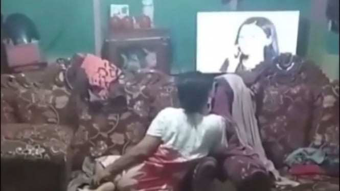 Seorang wanita asyik nonton tv.