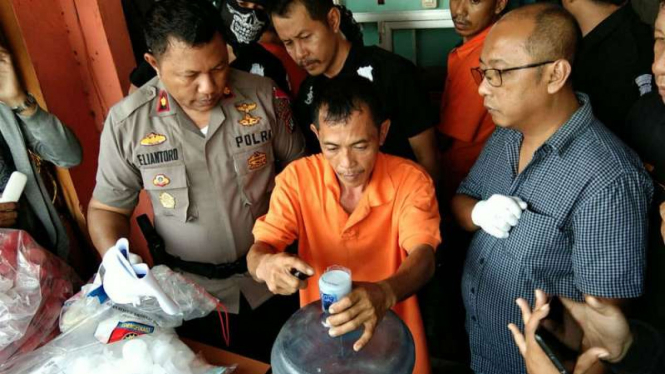 Polisi memperlihatkan seorang tersangka pemalsu air mineral kemasan galon mendemonstrasikan aksi kejahatannya di kantor Polsek Jatiuwung, Tangerang, Banten, pada Jumat, 28 September 2018.