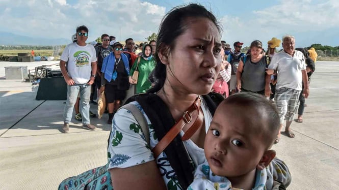 Warga terdampak gempa dan tsunami menunggu masuk ke dalam pesawat untuk dievakuasi di Palu, Sulawesi Tengah.