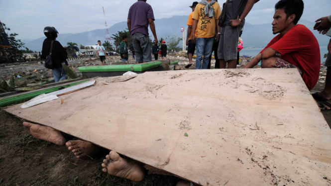 Warga berusaha mengidentifikasi anggota keluarganya di antara jenazah korban gempa dan tsunami di Pantai Talise Palu, Sulawesi Tengah