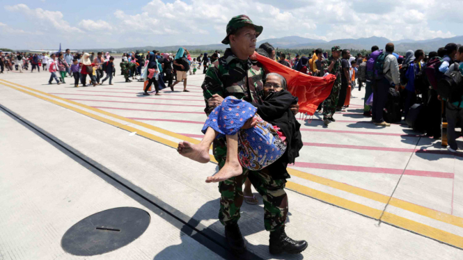 Prajurit TNI menggendong pengungsi berusia lanjut korban gempa dan tsunami di Bandara Mutiara Sis Al Jufri, Palu, Sulawesi Tengah