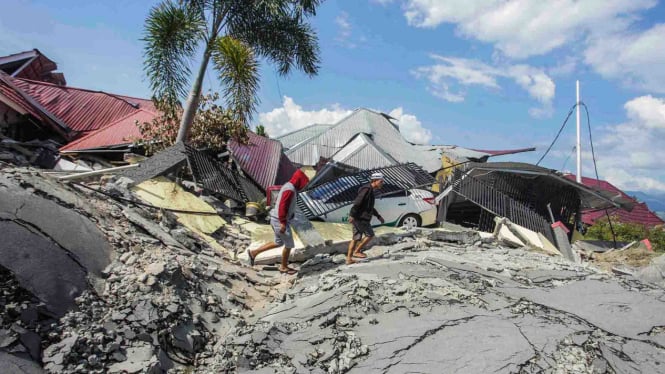 Warga melintasi jalanan yang rusak akibat gempa 7,4 pada skala richter (SR), di kawasan Kampung Petobo, Palu, Sulawesi Tengah, Selasa, 2 Oktober 2018.