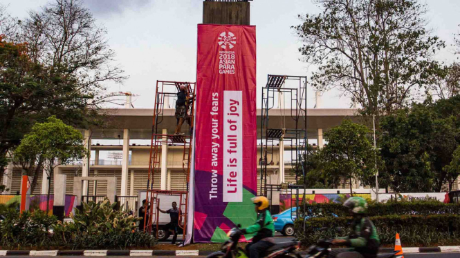 Pekerja memasang spanduk promosi Asian Para Games 2018 di kawasan Senayan, Jakarta