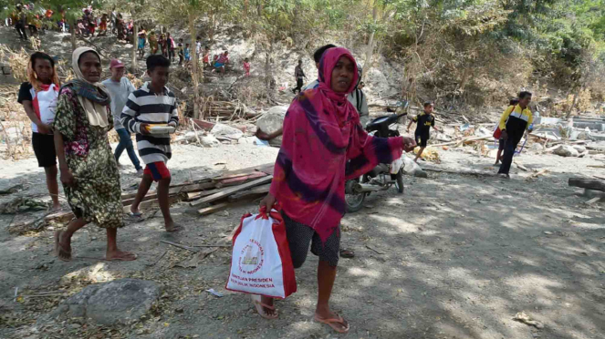 Warga korban gempa dan tsunami membawa bantuan dari Persiden Joko Widodo di Desa Loli Saluran, Donggala, Sulawesi Tengah, Rabu, 3 Oktober 2018.