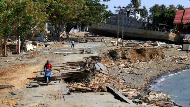 Warga berada di dekat kapal TNI AL yang terdampar di jalanan akibat tsunami di Watusampu, Ulujadi, Palu, Sulawesi Tengah, 3 Oktober 2018.