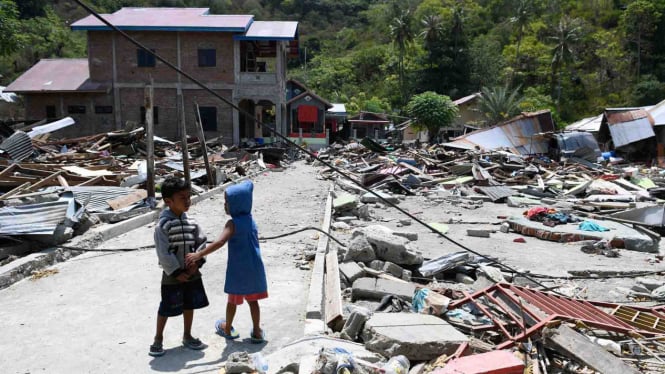 Dua anak bermain di antara reruntuhan bangunan yang rusak akibat gempa 7,4 pada skala richter (SR), di kawasan Loli Saluran, Donggala, Sulawesi Tengah, Rabu, 3 Oktober 2018.