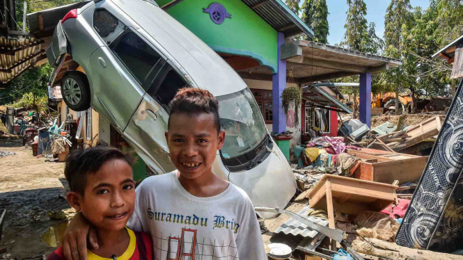 Dua anak berpose di depan rumah mereka yang rusak pascagempa dan tsunami di Desa Loli Saluran, Kecamatan Banawa, Donggala, Sulawesi Tengah, Rabu, 3 Oktober 2018.