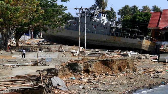 Warga berada di dekat kapal TNI AL yang terdampar di jalanan akibat tsunami di Watusampu, Ulujadi, Palu, Sulawesi Tengah, 3 Oktober 2018.