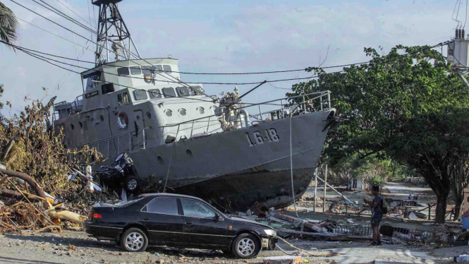 Warga mengabadikan kapal TNI AL yang terdampar di jalanan akibat gempa tsunami di Watusampu, Ulujadi, Palu, Sulawesi Tengah, Kamis, 4 Oktober 2018.