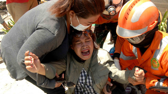 Keluarga korban menangis saat menyaksikan jenazah keluarganya dievakuasi yang menjadi korban gempa bumi dan tsunami di Hotel Mercure, Palu, Sulawesi Tengah