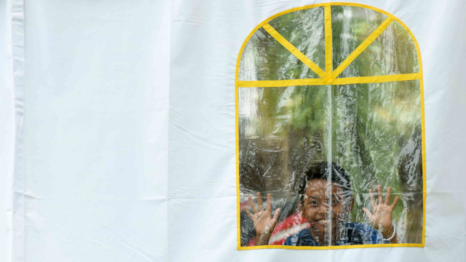 Seorang anak pengungsi gempa dan tsunami Palu mengintip dari jendela tenda pengungsian di halaman kantor RRI Palu, Sulawesi Tengah