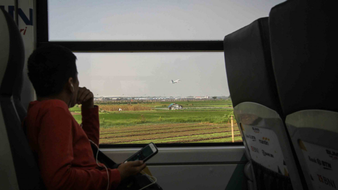 Penumpang melihat pesawat terbang dari dalam kereta bandara Railink di Tangerang