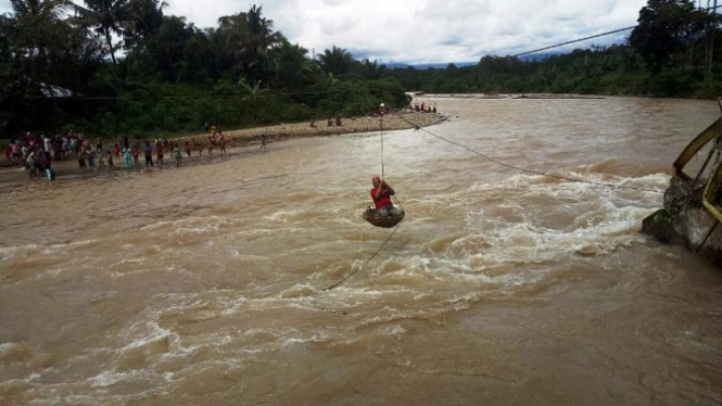 Anggota Komisi II DPR Agus Susanto bergelantungan menembus banjir di Pasaman