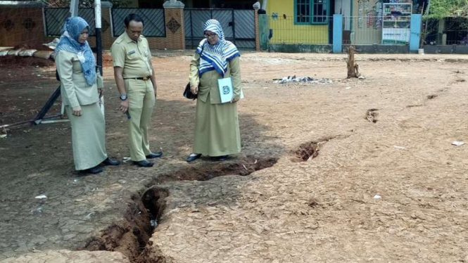 Staf Pemerintah Kota Depok melihat kondisi tanah terbelah.