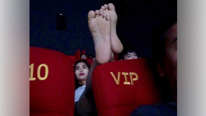 Wanita ini naikkan kakinya saat menonton bioskop.